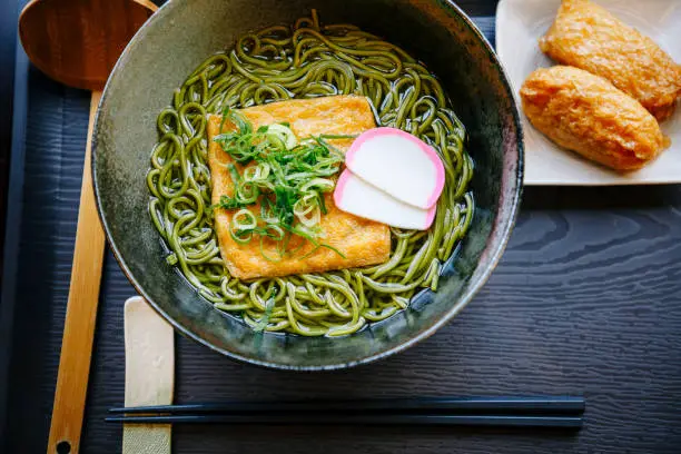 Japanese noodle soup with cha soba noodles (green tea soba), abura-age (slice of deep fried tofu) and inarizushi as a side dish.