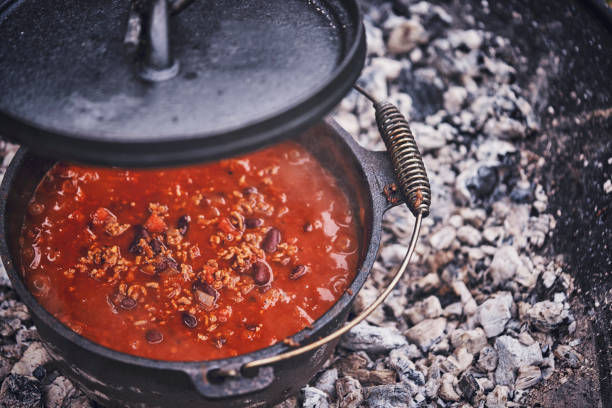 koken chili con carne in de nederlandse oven over logfire - chili fire stockfoto's en -beelden