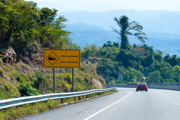 istock Caution Long Descent 2.5km downhill road sign on highway through mountains in scenic countryside. 1153700388