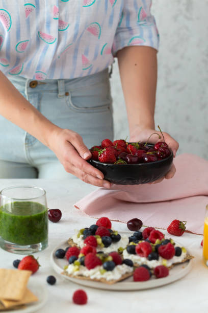 vista frontal de pan tostado con mantequilla de maní de chocolate, bayas de temporada sobre fondo blanco con mujer. sabroso desayuno dulce de verano con tostadas y bebidas saludables - flower cherry cup tea fotografías e imágenes de stock