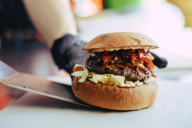 istock Cook preparing burger adding the sauce on the cream cheese. Three burgers. 1153706298