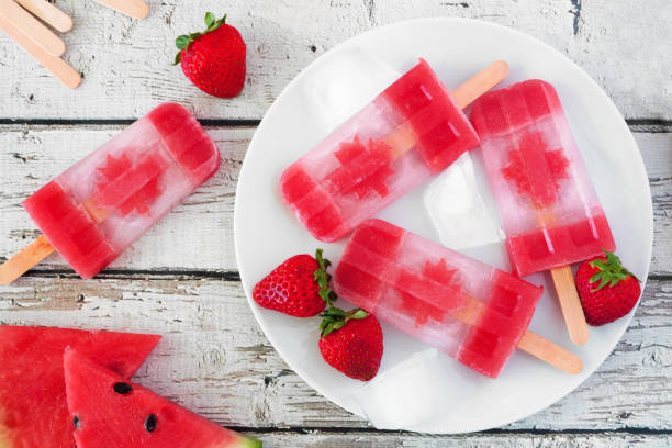 istock Canada Day flag popsicles, above scene on a rustic white wood background 1153706541