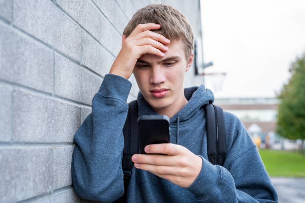 Upset teenager looking at his cellphone. stock photo
