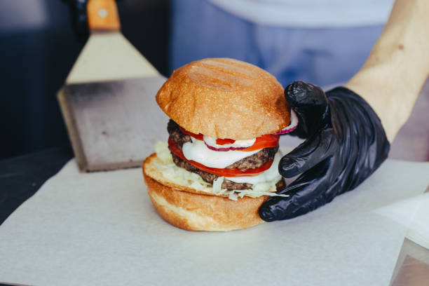 istock Cook preparing burger adding the sauce on the cream cheese. Three burgers. 1153707171