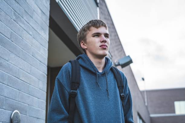 Sad teenager standing outside of a school. stock photo