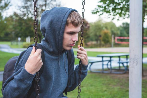 Sad teenager sitting on a swing. stock photo