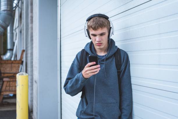 Sad teenager wearing headphones and listening to music. stock photo