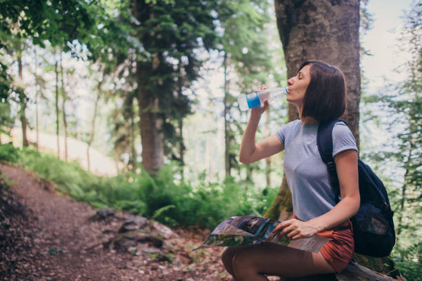 istock Woman resting drinking water while hiking in forest. 1153709254