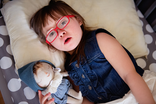 Little girl with down syndrome lying in a bed.  Photo was taken in Quebec Canada.