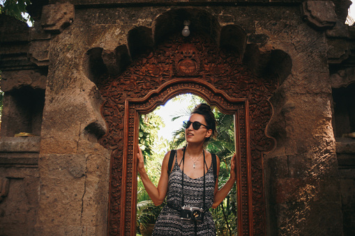 Young woman, solo tourist, walking through the old Hindu temples in Ubud, on the island of Bali, Indonesia.