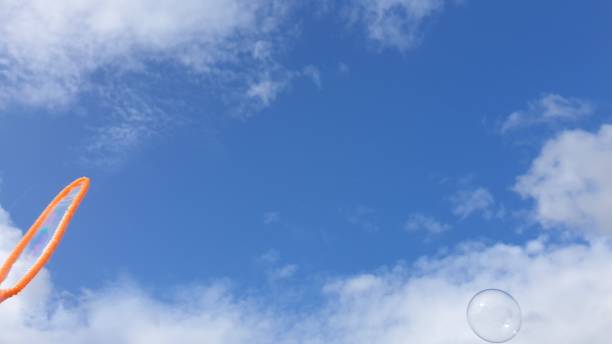 istock Soap bubble floating in blue sky with white clouds 1153714679