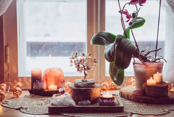 Feng Shui nature theme altar at home table and on window sill. Earth element( rock crystal clusters), wood element( wood discs), fire element( candles), rock salt candle holder. Positive home energy.