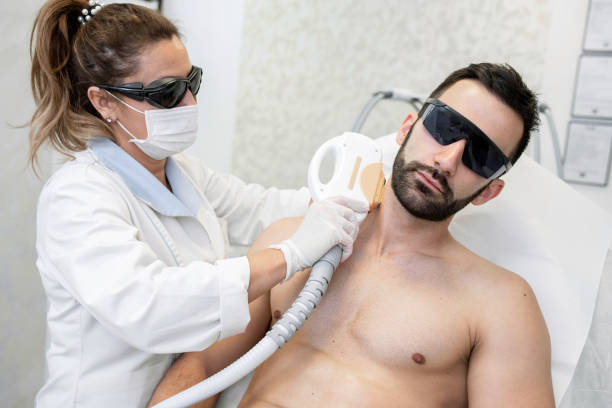 молодой человек в спа-салоне получает лазерную эпиляцию - laser therapy medical laser light therapy стоковые фото и изображения