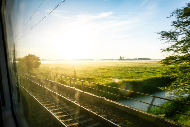 View out of train window on green fields of East German landscape at sunrise
