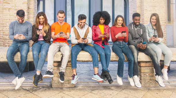 istock People from different cultures and country using smartphone together sitting on a bench. 1153724284