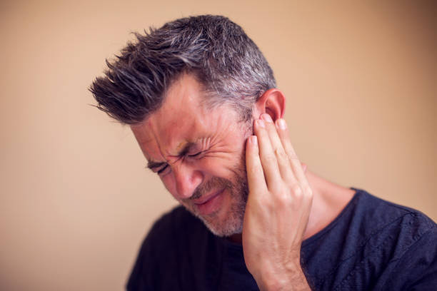 man feels ear pain isolated. people, healthcare and medicine concept - tinitus imagens e fotografias de stock