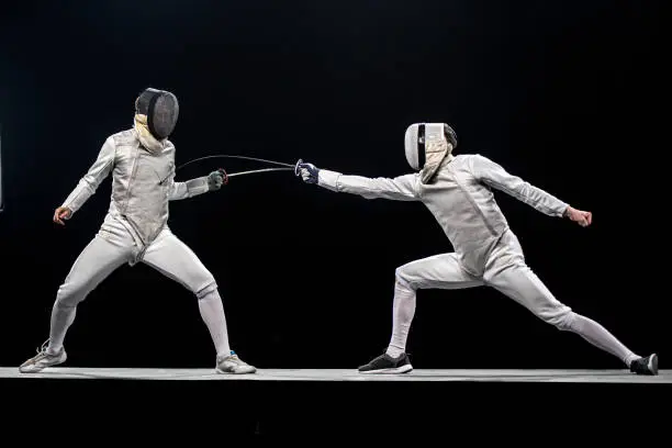 Two fencers duelling isolated on black background, copy space.