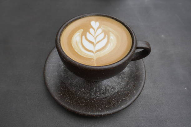 istock Coffee, Cappuccino with an artistic milk foam pattern in a brown cereamic cup on a dark background 1153731475