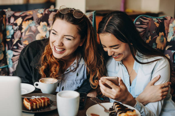 istock Two beautiful young girlfriends having fun laughing while looking at a laptop screen while sitting in a coffee shop. 1153731642