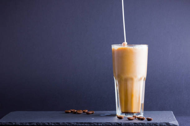 istock Iced coffee with milk on a dark background. Summer drink with caffeine on the slate board. Latte in a glass cup and coffee beans. Copy space 1153733382