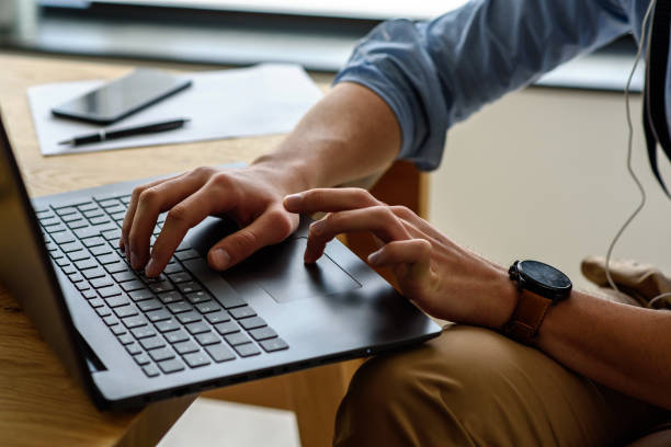 istock Young modern bearded man working with laptop computer indoors 1153734236