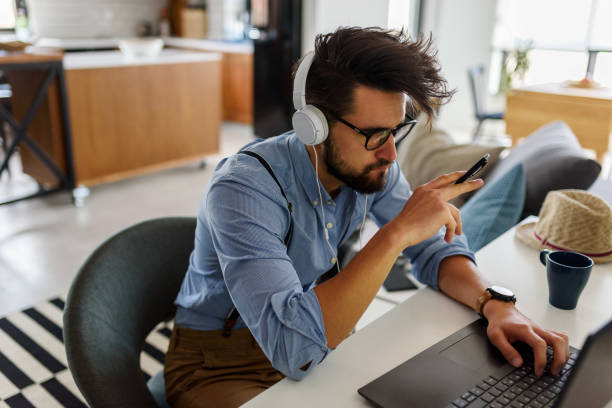 istock Young modern bearded man working with laptop computer indoors 1153734351