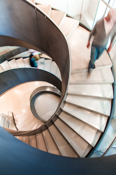 istock Motion Blur of People on Abstract Spiral Staircase 1153734424