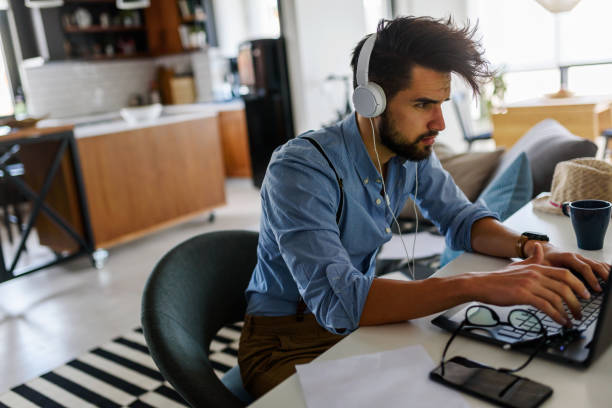 istock Young modern bearded man working with laptop computer indoors 1153734557