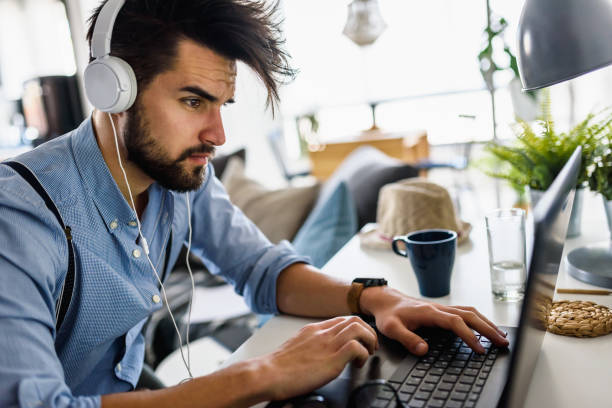 istock Young modern bearded man working with laptop computer indoors 1153735483