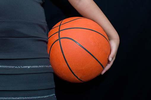 A woman holds the basketball in the hand in studio
