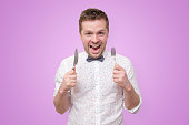 Man holding fork and knife on hand ready to eat