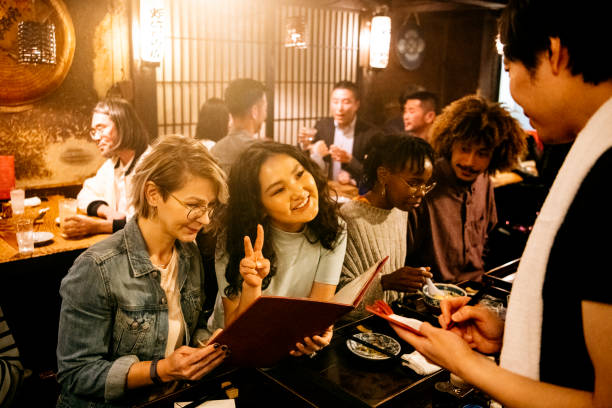 Candid portrait of young women ordering food in restaurant Waiter in Izakaya taking food order from attractive young women choosing from menu, making peace sign, dining, fun, leisure central asian ethnicity stock pictures, royalty-free photos & images