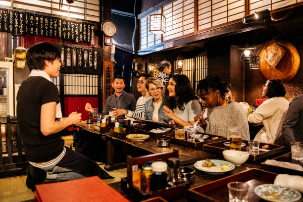 Group of friends ordering food in Japanese Izakaya Waiter taking food order from happy group of friends, night out, drinking, eating central asian ethnicity photos stock pictures, royalty-free photos & images