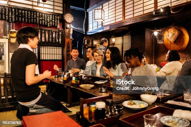 Group Of Friends Ordering Food In Japanese Izakaya Stock Photo - Download Image Now - Japan, Restaurant, Tourist