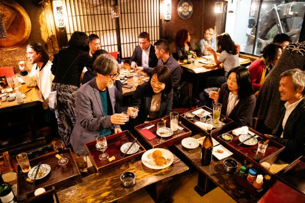 Co-workers eating dinner together in Japanese restaurant, celebrations, fun, togetherness