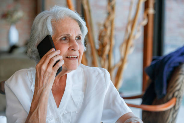 istock Relaxing senior woman using mobile phone while sitting in living room 1153740541