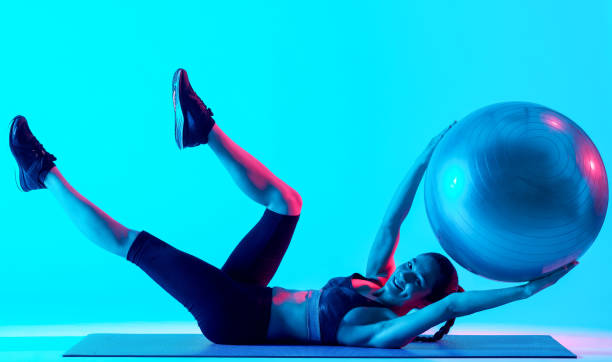 женщина exercsing фитнес пилатес exercices изолированы - lying on back women studio shot looking at camera стоковые фото и изображения