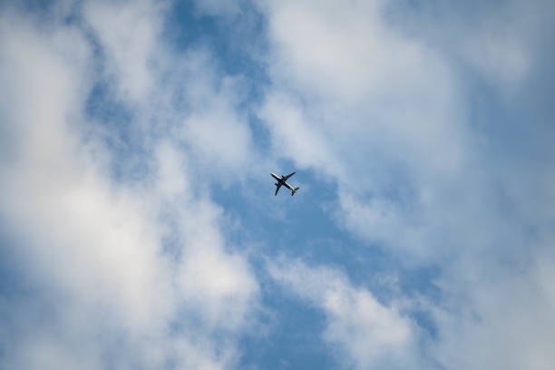 istock An airplane in the sky underneath white patches of clouds. 1153748030