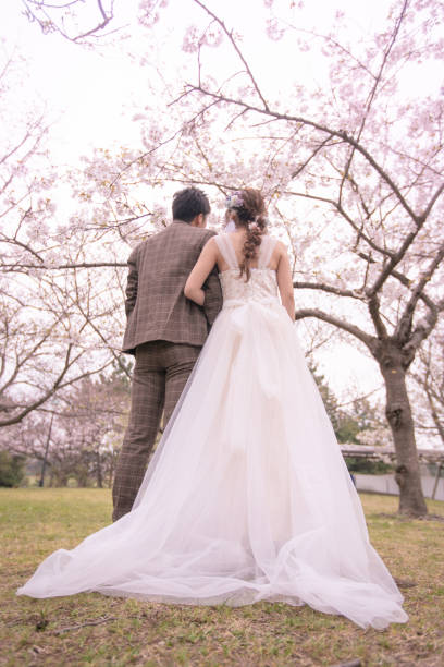 istock Happy bride and groom walking under cherry trees 1153751227