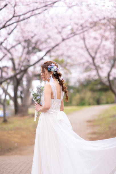 istock Happy bride standing in cherry blossom field 1153751229