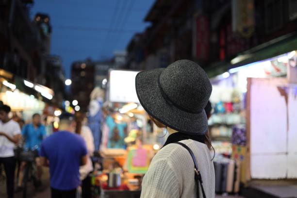 istock Young woman walking at night market 1153752276