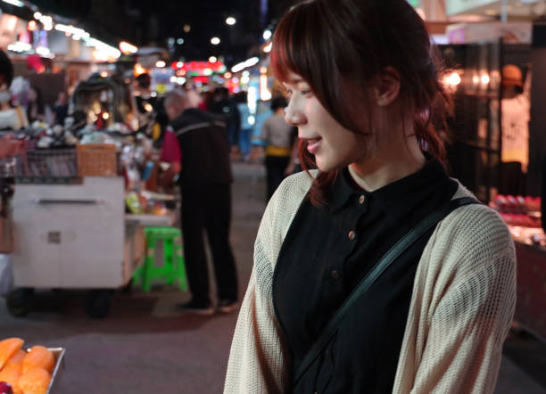 istock Young woman walking at night market 1153752304