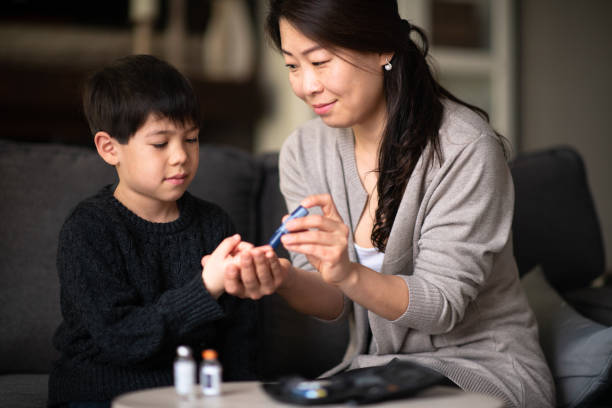 madre ayudando a hijo a revisar los niveles de azúcar en sangre - insulin fotografías e imágenes de stock