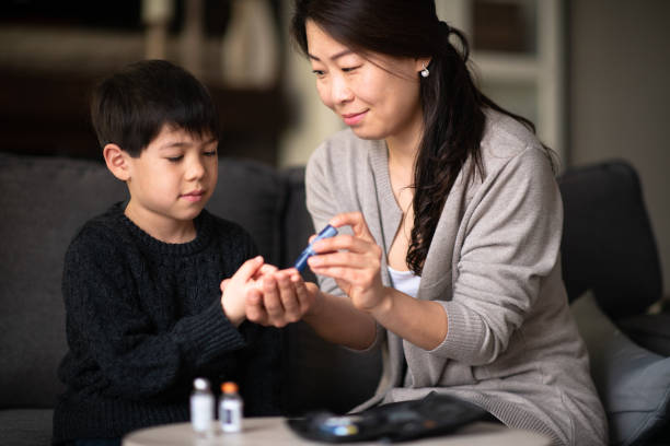 Mother helping son check blood sugar levels A mother and son are sitting together in a living room. She is helping him check his blood sugar levels because he is diabetic. insulin stock pictures, royalty-free photos & images