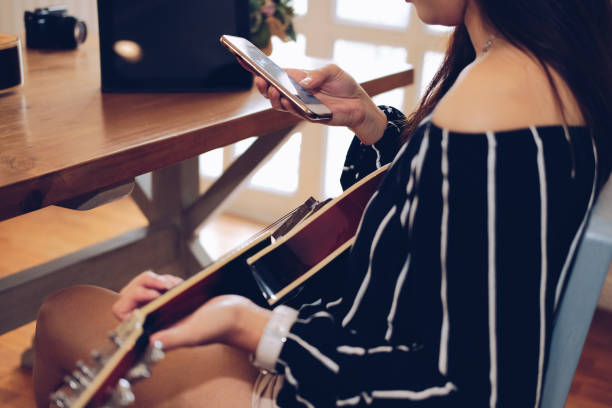 istock woman playing guitar using mobile smart phone 1153753970