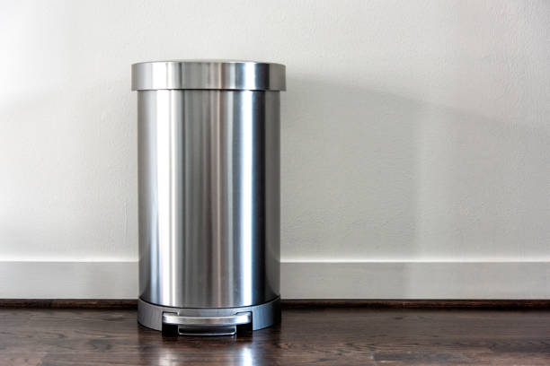 Stainless Steel Trash Can A contemporary stainless steel trash can atop a hardwood floor. wastepaper basket photos stock pictures, royalty-free photos & images