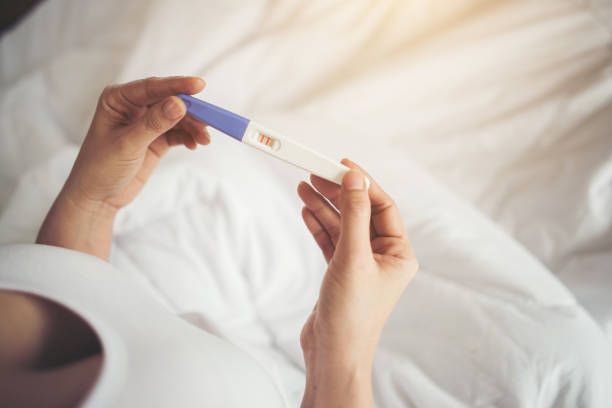 istock Young woman hand holding pregnancy test 1153755386