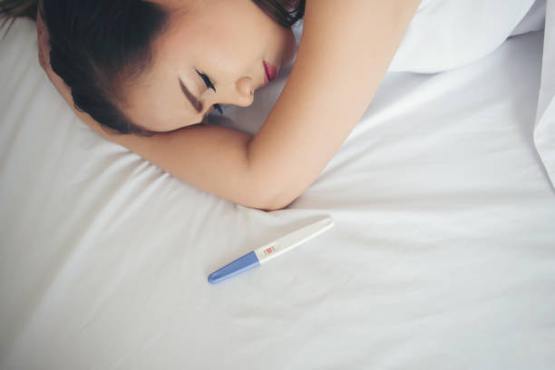 istock Sad woman complaining holding a pregnancy test sitting on bed 1153755419