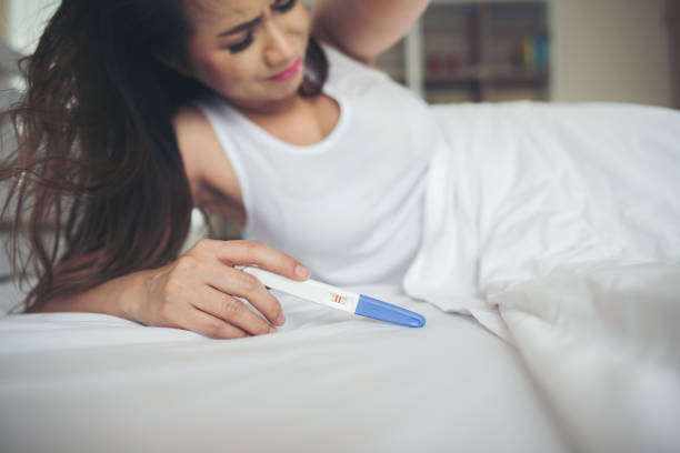 istock Sad woman complaining holding a pregnancy test sitting on bed 1153755455