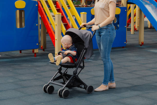 istock Young mom with a baby in a stroller at the playground 1153757512